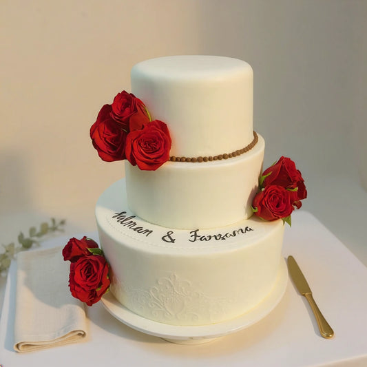 3-tier ivory wedding cake decorated with fresh crimson red roses and delicate embossed detailing by PuffyClouds in Kochi