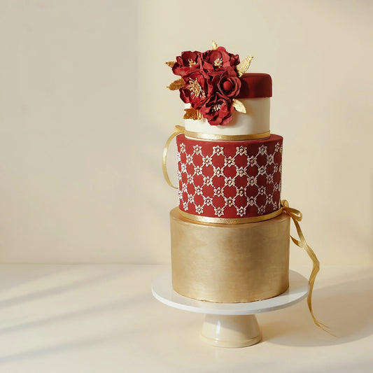 3-tier luxurious floral wedding cake with burgundy sugar flowers, intricate detailing, and elegant gold accents by PuffyClouds, Kochi