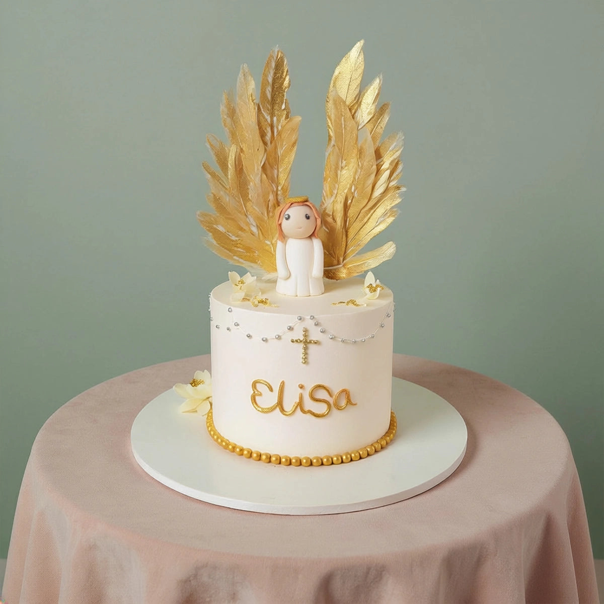 A single-tier ivory baptism cake featuring a fondant angel figurine with large upright golden wafer paper wings, decorated with a gold cross and edible pearls by PuffyClouds in Kochi