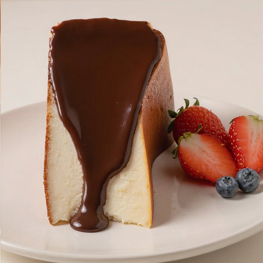 Slice of creamy Basque cheesecake with rich chocolate sauce, served with fresh strawberries and blueberries.